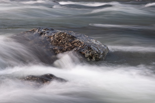 Abstract background from long exposure of water stream in a mountain river close-up