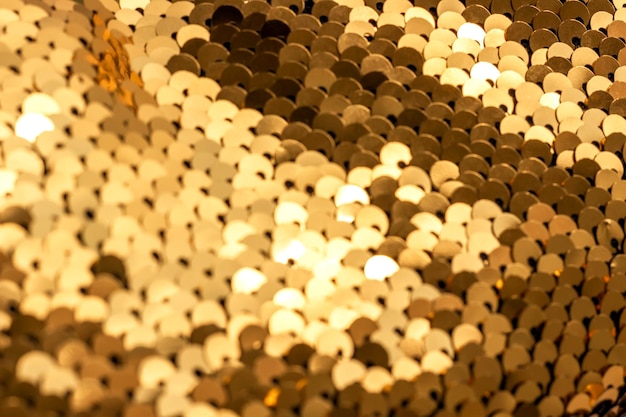 Abstract background of golden sequins with selective focus as texture