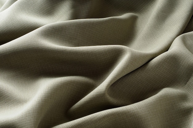 Abstract background, gray luxurious fabric lies in wavy folds, close-up. Elegant design. Texture fabric shimmers in the soft light. Silky, wrinkled, dark fabric.