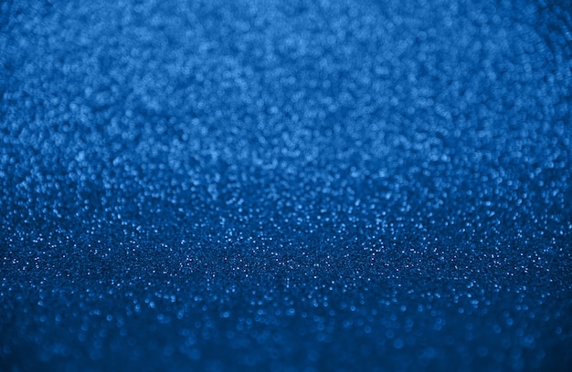 Abstract background of indigo blue bokeh defocused blurred lights and glitter sparkles