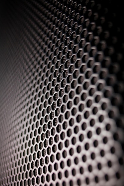 Abstract background is a black metal grid for the speaker close-up. Details audio equipment.