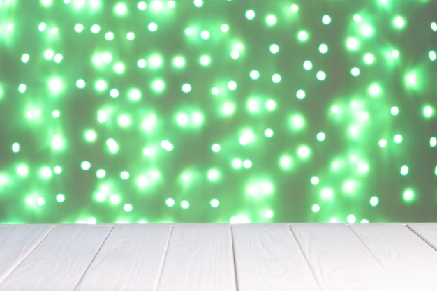 Абстрактный фон макет Расфокусированные зеленые огни боке и белая деревянная поверхность