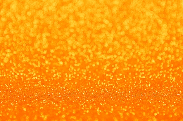 Abstract background of orange, golned and yellow vivid bokeh defocused blurred lights and glitter sparkles