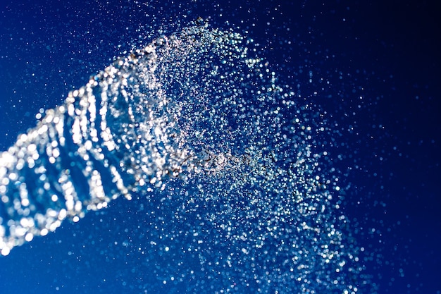 Abstract background. A stream of water with splashes sparkles on a blue background. Motion blur. Selective shallow focus.