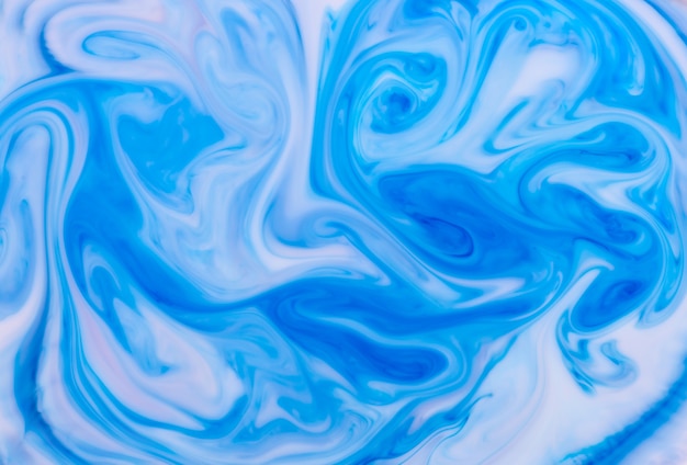 Photo abstract background of swirling blue waves of ink in water forming an artistic flowing monochromatic pattern for use as a design template