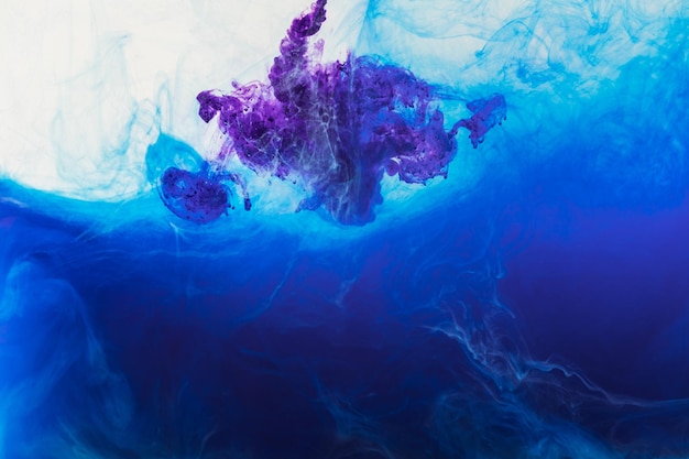 Abstract background with blue and purple paint flowing in water