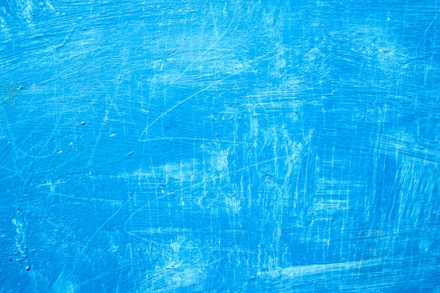 Abstract background with textured strokes of blue paint on the wooden surface 