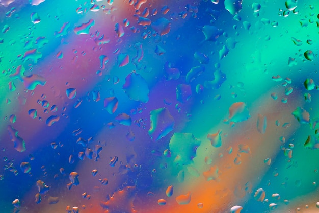 虹のすべての色で多色の背景に水滴と抽象的な背景