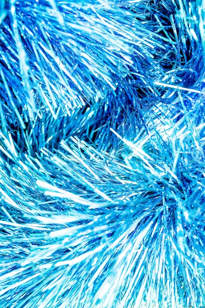 abstract blue bokeh defocused background.New Year background photo with glowing blue tinsel. Close-up of shiny metallic texture of holiday decoration.Glitter sparkling abstract blue bokeh defocused