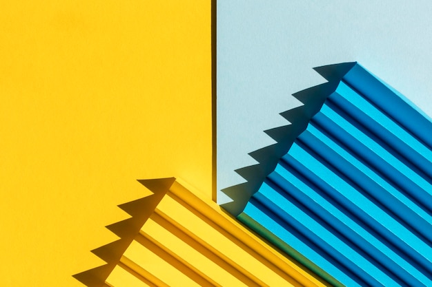 Photo abstract blue and yellow colored paper texture folded paper with harsh sun shadows geometric shapes and lines minimalist background flat lay copy space