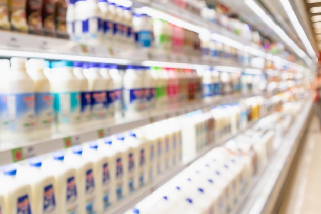 抽象的なぼかしスーパーマーケットの食料品店の冷蔵庫の棚に新鮮な牛乳瓶や乳製品が入っています