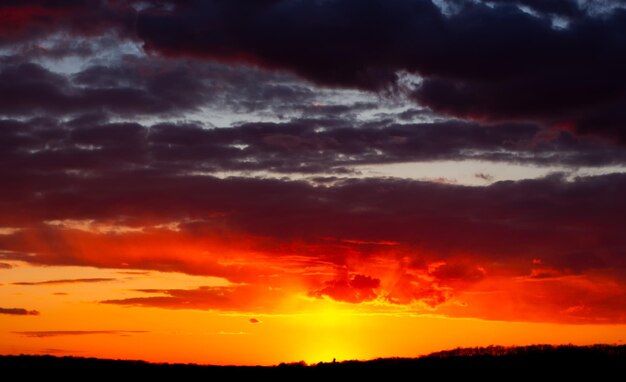 Abstract burning sky at sunset Red clouds on the horizon are illuminated by evening sunlight