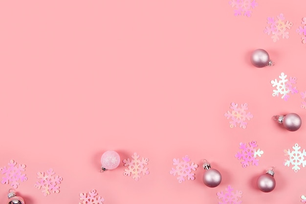 Абстрактный новогодний фон в розовых розовых конфетти и новогодние шары на розовом фоне.