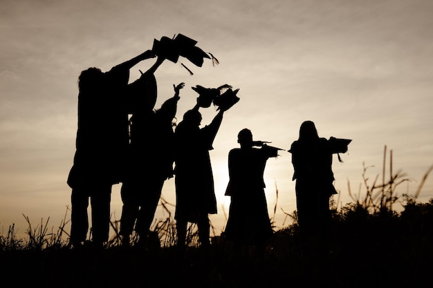 Foto abstract primo piano gruppo di vista posteriore dei laureati al tramonto silhouette