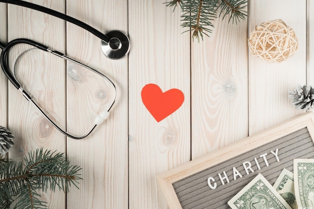 Abstract composition nameplate charity with money stethoscope red heart and spruce twigs as decoration on wooden view