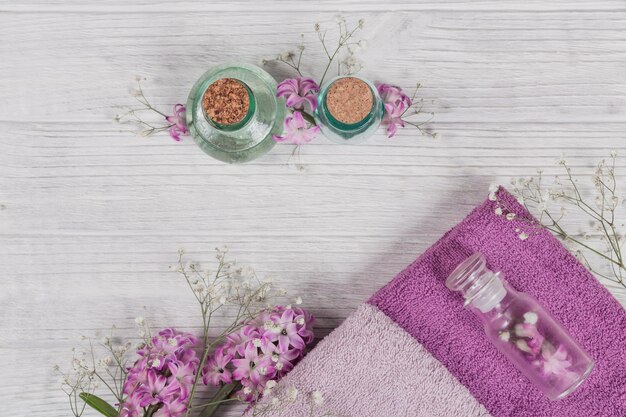 ピンクのヒヤシンスの花のタオルとエッセンシャル オイルとオーガニック化粧品のボトルの抽象的な構成