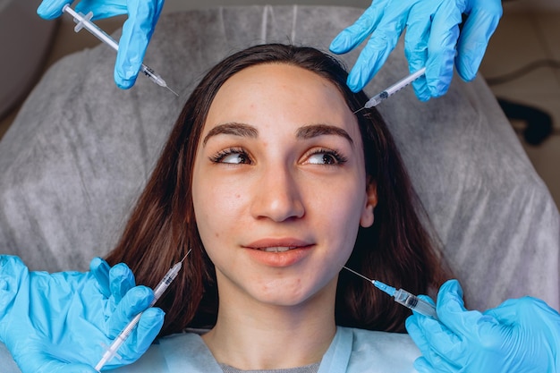 Abstract composition of a young pretty woman on a white couch among syringes for cosmetic injections.