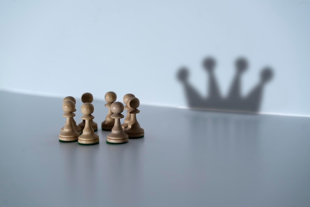 The abstract concept chess pawns make a shadow of queen or king crown