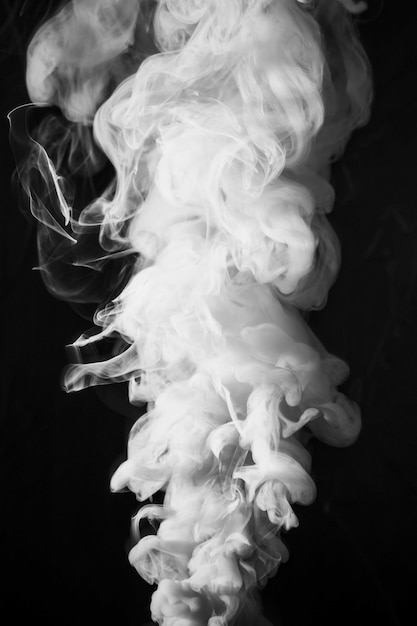 Abstract dense fluffy puffs of white smoke on black background