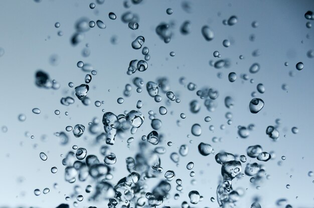 Abstract falling drops of water on a light background close-up