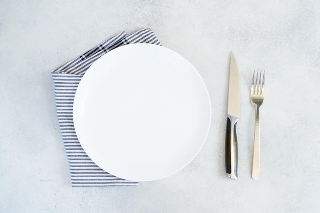 Abstract food background empty white plate with blue napkin and cutlery