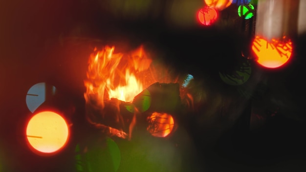 Abstract footage of burning fire in fireplace, Christmas tree and glowing colorful lights