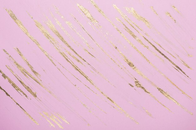 Abstract Gold potal brush strokes on pink pastel paper background or texture.