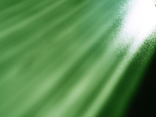 Abstract green background Light beams with flickering dots Lines and stripes from top left to bottom right Diagonal parallel and asymmetric lines stripes rays and beams