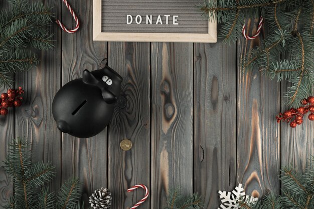 크리스마스 잔가지와 사탕 장식 복사 공간에 황금 동전이 있는 검은 돼지 저금통이 있는 추상 휴일 구성