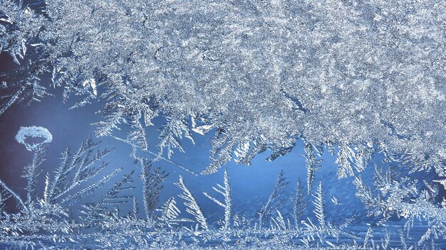 Abstract ice background, blue background with cracks on the ice surface. Frosty pattern on the winter window glass