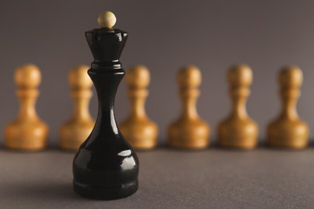 Abstract leadership business concept with chess pieces. Queen figure standing against line of small pawns, copy space