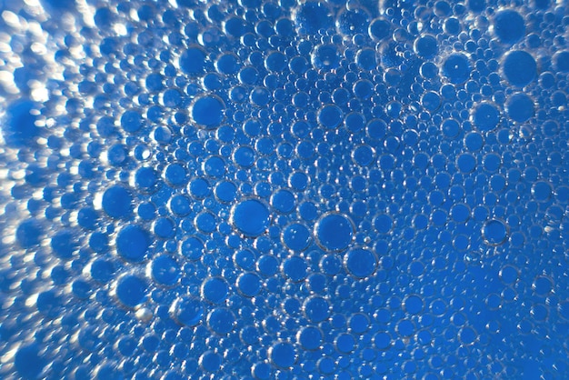 Abstract light blue background with oil circles bubbles of\
water close up oil bubbles in the water macro