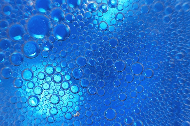 Abstract light blue background with oil circles bubbles of
water close up oil bubbles in the water macro