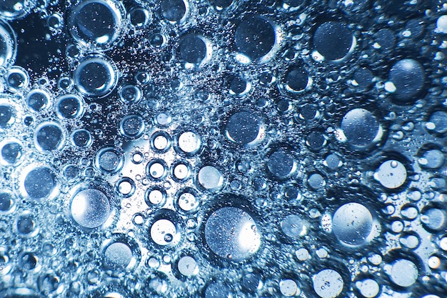 油の円と水の泡の抽象的な水色の背景がクローズアップ