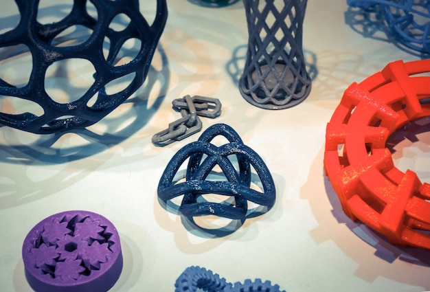 Abstract models printed by 3d printer close-up. Bright colorful objects printed on a 3d printer on a white table. Progressive modern additive technology. Concept of 4.0 industrial revolution