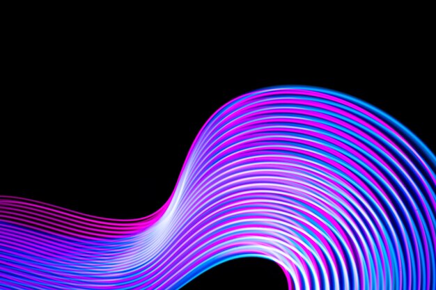 Photo abstract neon modern pink and blue waves curvy lines on black background. technology data.