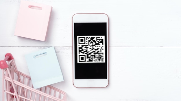 QR 코드 디자인 개념 요소를 사용한 추상 온라인 쇼핑모바일 결제 나무 테이블 배경에 있는 다채로운 카트 페이퍼 백