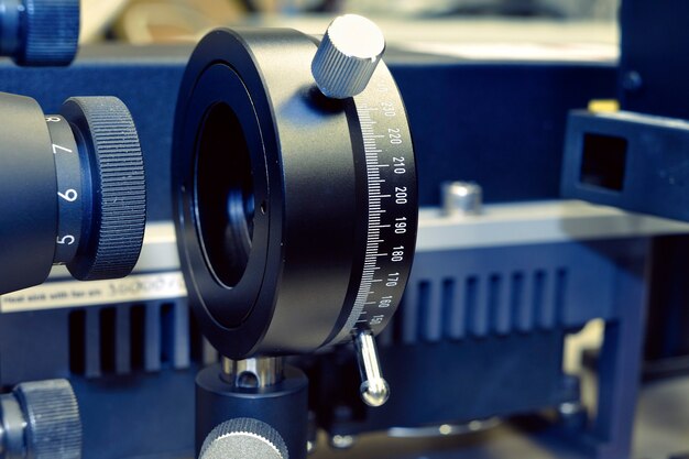 Abstract optomechanical fragment inside optical laboratory; selective focus on the plate with numbers