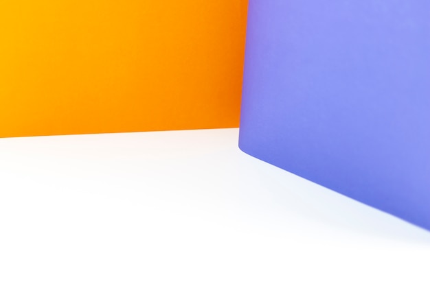 白いテーブルにオレンジと紫色のカラーペーパーの背景を抽象化します。