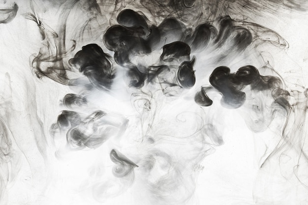 水の背景の抽象的なペイント。白いアクリルの渦巻きのしぶきで動いている黒い煙の雲