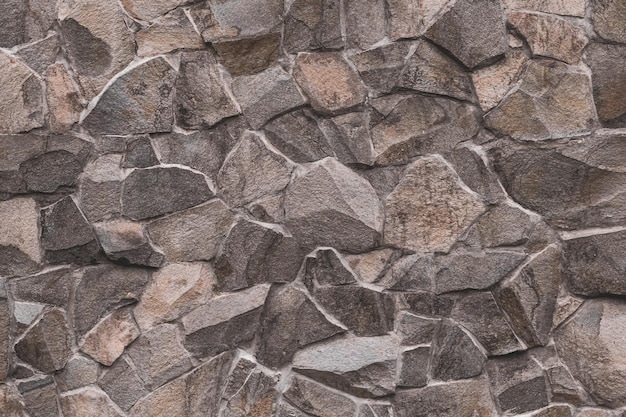 Abstract pattern of brown stone texture Brick wall background Rough granite surface Cracked rock Decorative tile on facade of building