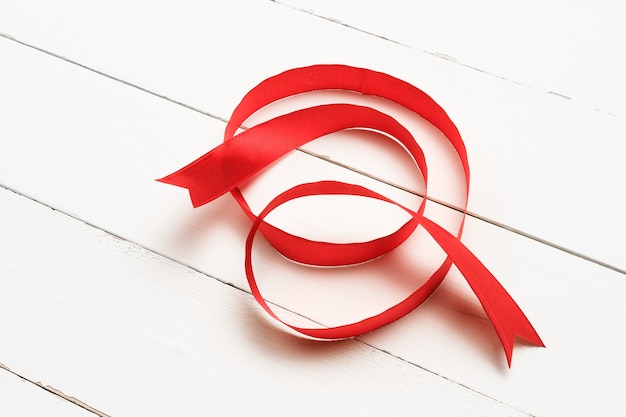 Photo abstract red silk ribbon on white wooden background