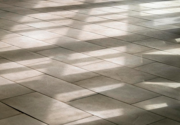 Foto linee di sagome di ombre astratte sul pavimento piastrellato attraverso una finestra durante la giornata di sole