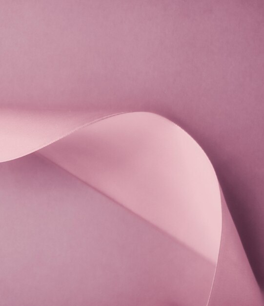 赤みを帯びたピンクの背景に抽象的なシルク リボン ホリデー セール製品プロモーションとグラマー アート招待状カードの背景の排他的な高級ブランド デザイン