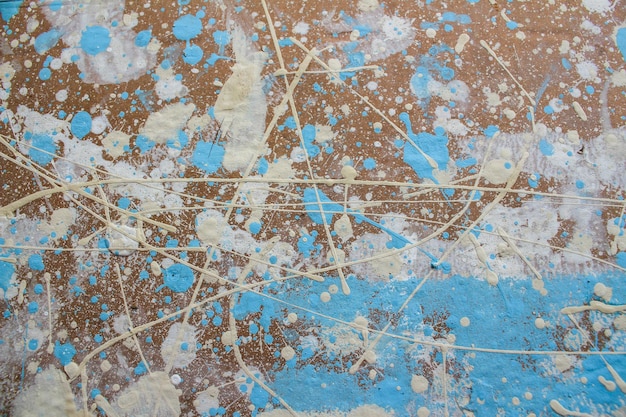 Abstract spots drops of yellow blue white paint on a brown wooden surface