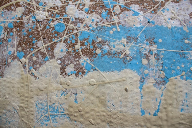 Abstract spots drops of yellow blue white paint on a brown wooden surface