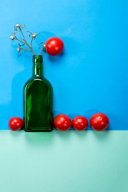 Photo abstract still life with tomato and glass bottle on a multicolored background