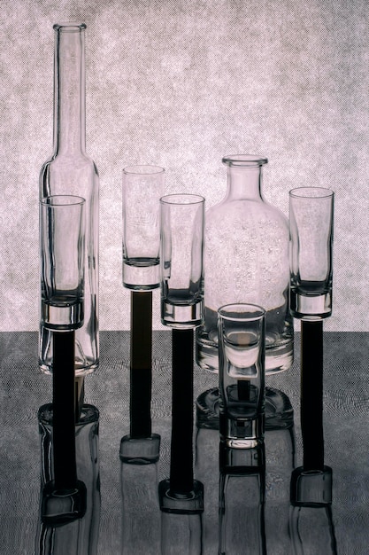 Abstract stilleven met fles en glazen glazen op stands op een grijze achtergrond