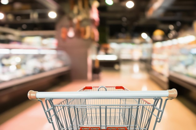 空の赤いショッピングカートで抽象的なスーパーマーケットの食料品店のぼやけた焦点ぼけの背景