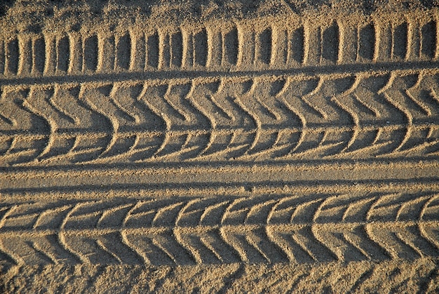 Foto tracce di pneumatici a consistenza astratta nella sabbia grossolana della spiaggia